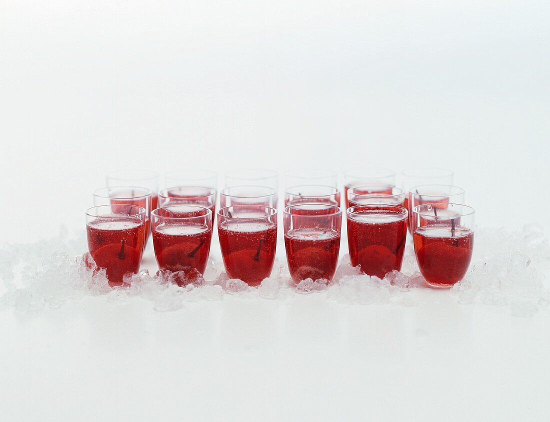 Lots of schnapps glasses on crushed ice with cherry liqueur and cherries