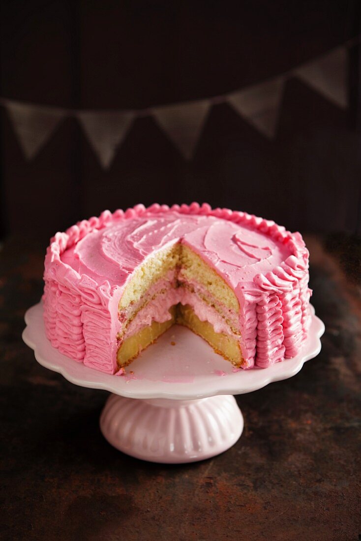 Raspberry layer cake on a cake stand, cut to show the inside