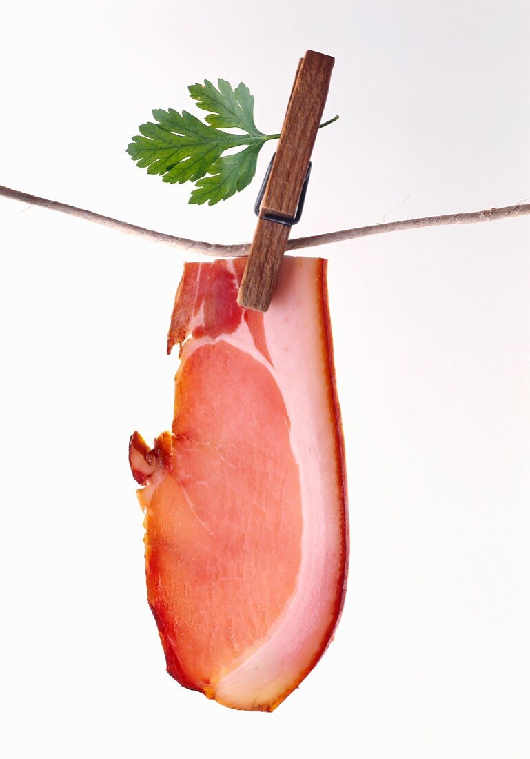 A rasher of bacon hanging from a washing line by a clothes peg