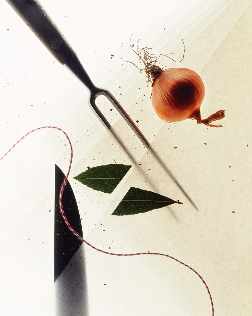 A still life featuring a knife, a meat fork, an onion, a bay leaf and kitchen string