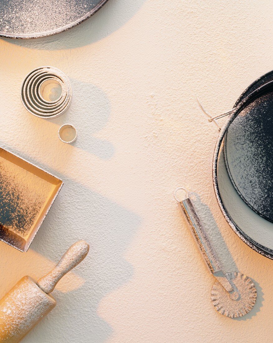 Baking tins and utensils on a floured work surface