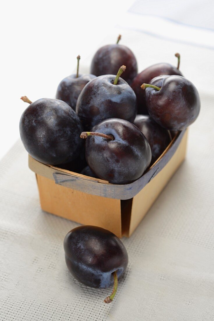 Fresh plums in woodchip basket