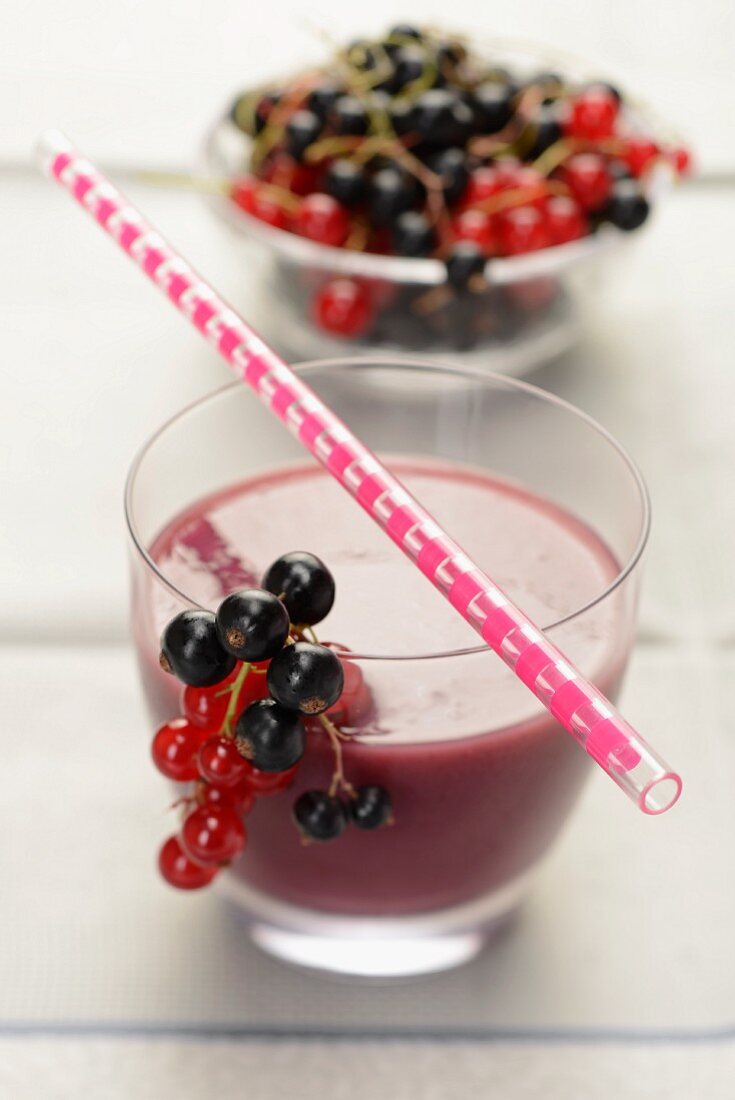 A smoothie made of black- and redcurrants, with fresh currants and a drinking straw