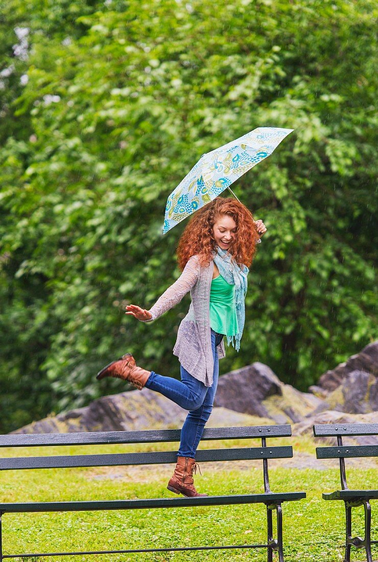 Woman with umbrella skipping through park