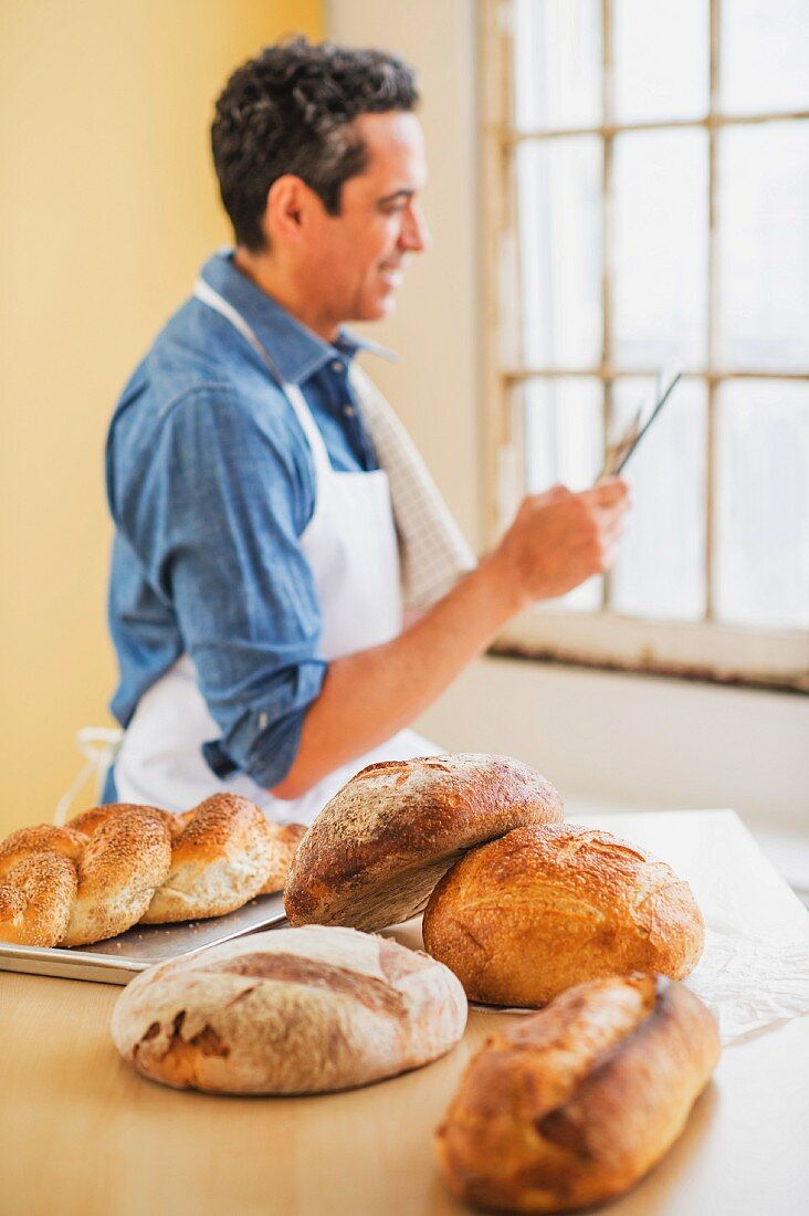 Mann mit Schürze & frisch gebackenen Broten