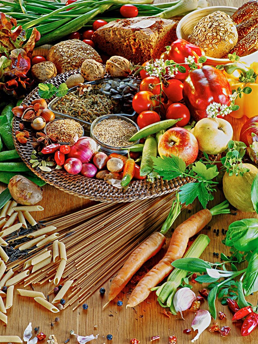 A mixed still life featuring vegetables, fruit, cereals, pasta and bread