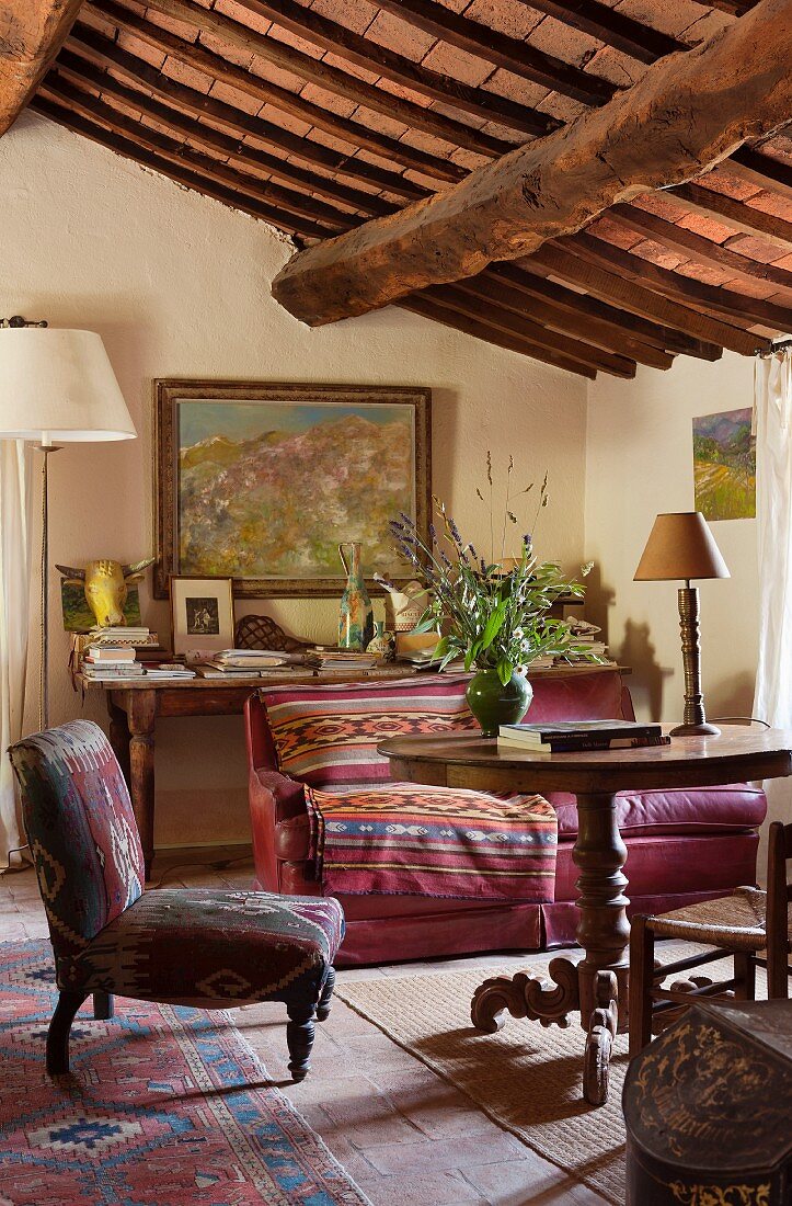 Wohnzimmer im rustikal gemütlichen Landhausstil mit gemustertem Polstersessel und künstlerischem Ambiente
