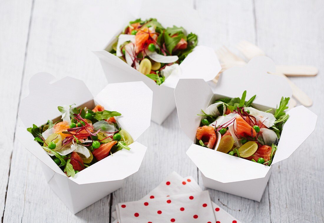 Rocket salad with salmon trout, grapes and peas in takeaway containers