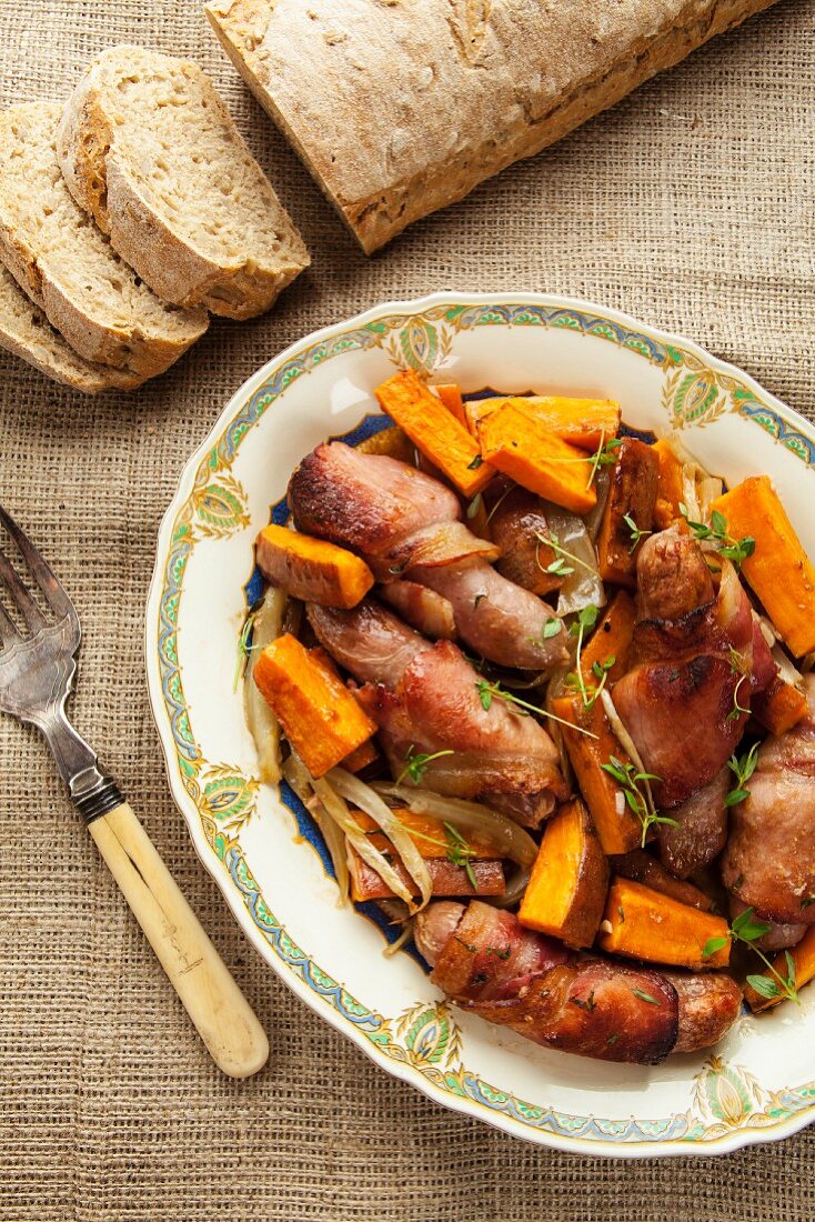 Mini sausages wrapped in bacon with sweet potatoes and bread