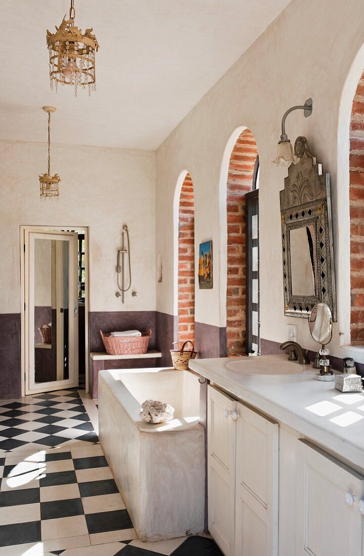 Spacious bathroom with bathtub, arched French windows and chequered floor