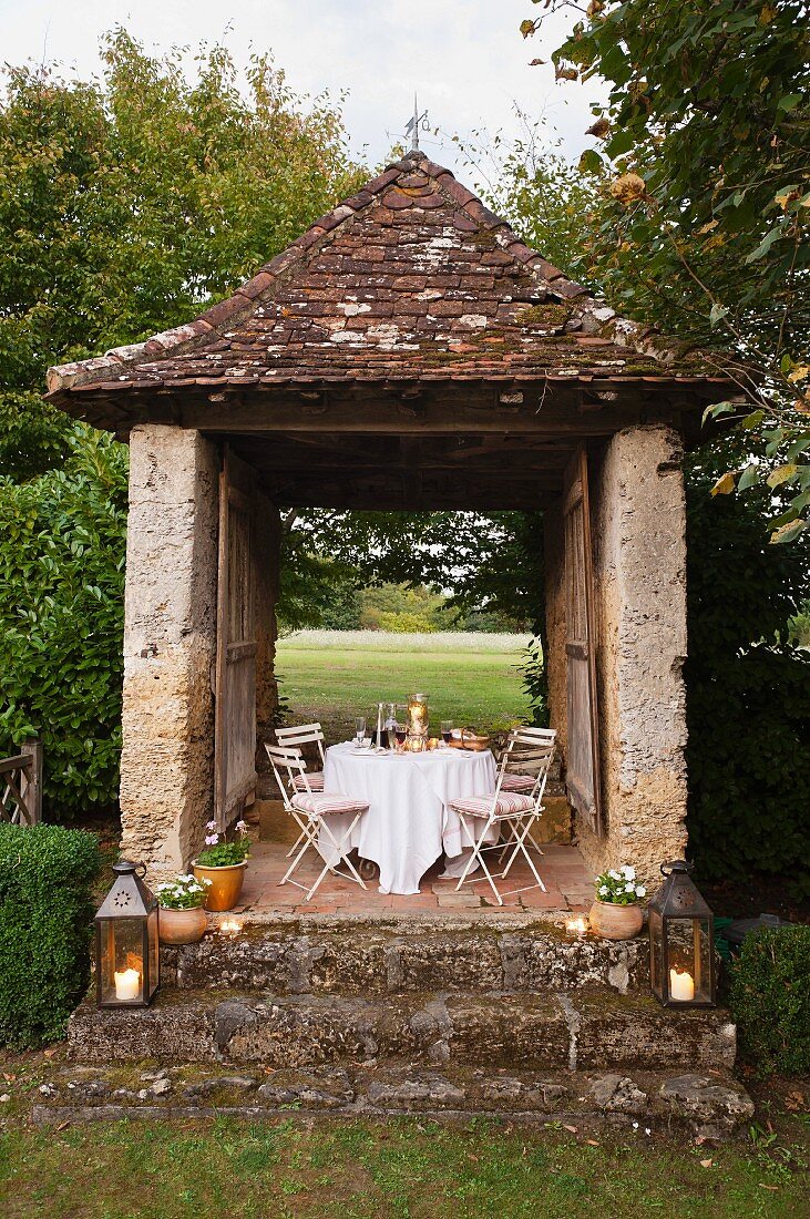 Set table in old, stone hut with lanterns on stone steps