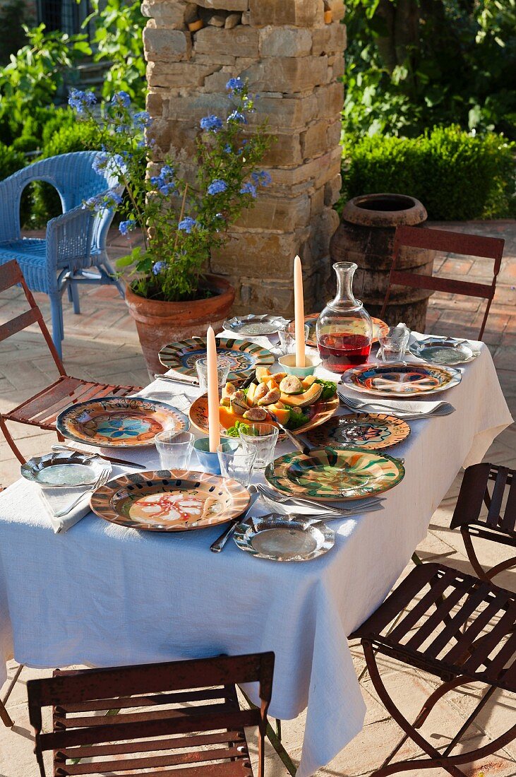 Garden table set with colourful crockery in summery, Mediterranean atmosphere