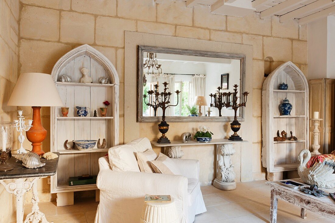 Limestone wall with shabby-chic wooden shelves, console table and mirror in restored, French country house