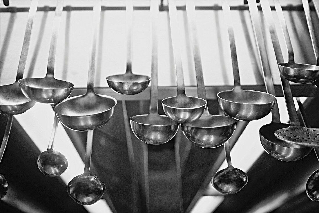 Lots of soup ladles hanging in a commercial kitchen