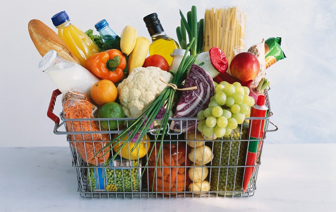 A shopping basket full of vegetables, fruit and groceries
