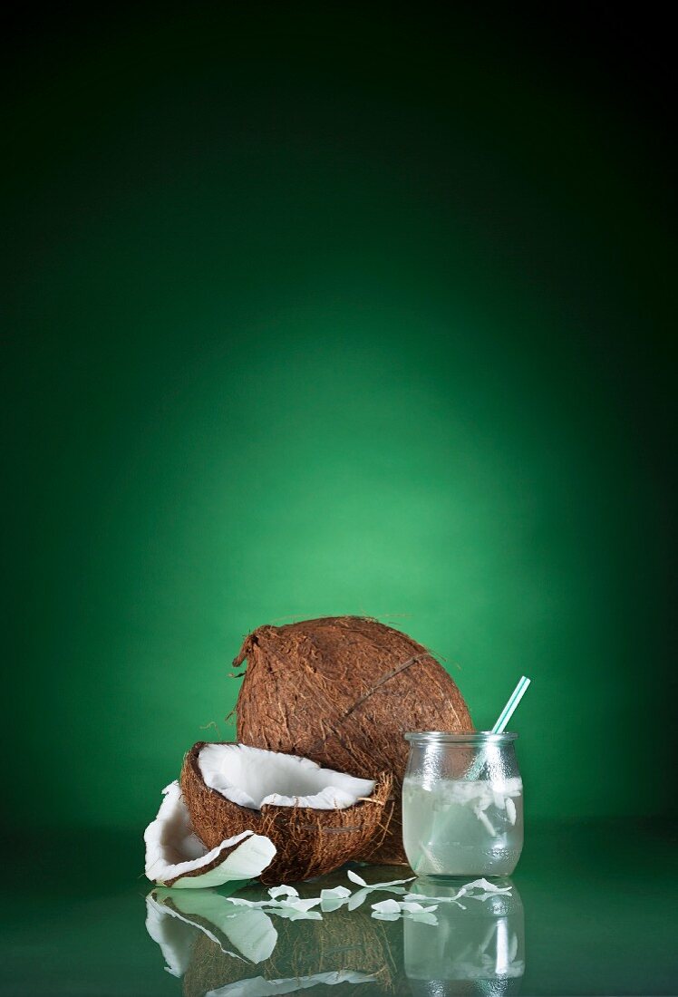 Ein Glas Kokoswasser mit einem Strohhalm und frische Kokosnuss