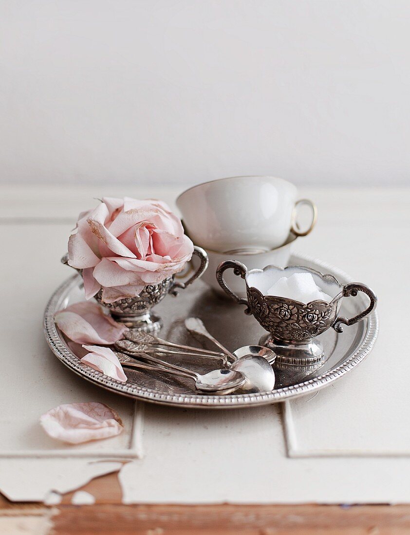 Antike Teetassen, Zuckerdose und rosa Rosenblüte