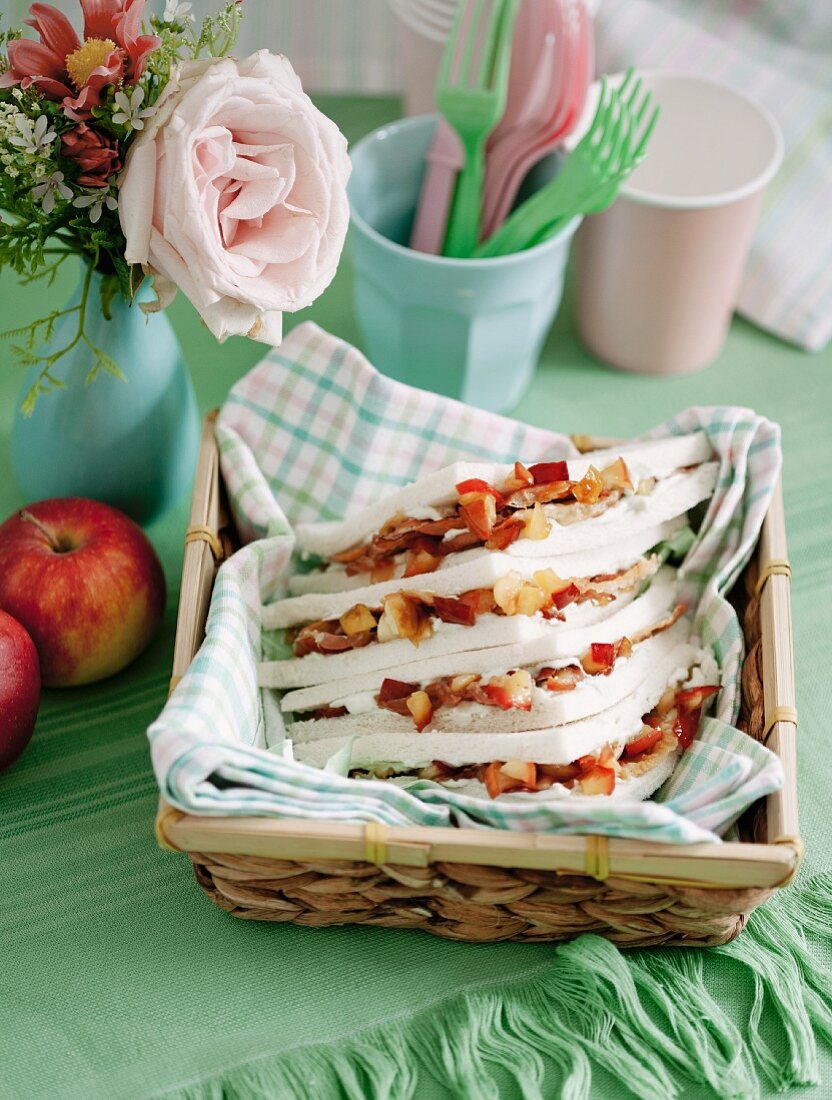 Tramezzini (Italian crustless sandwich triangles) with apple and cream cheese in a bread basket
