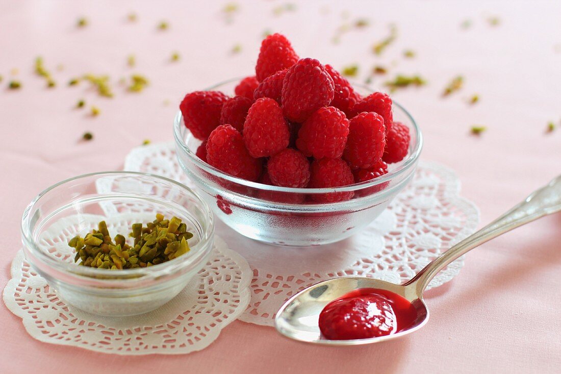 A spoon of raspberry and rose jam, chopped pistachios and fresh raspberries