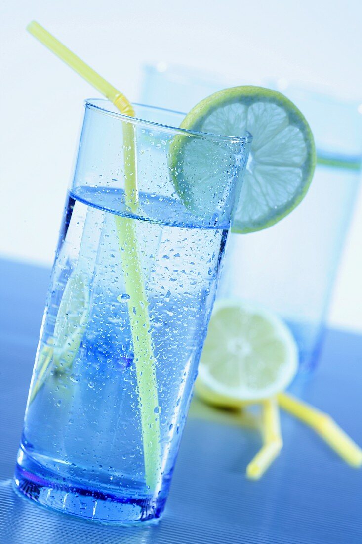 Blue glasses with water, lemons slices and yellow straws