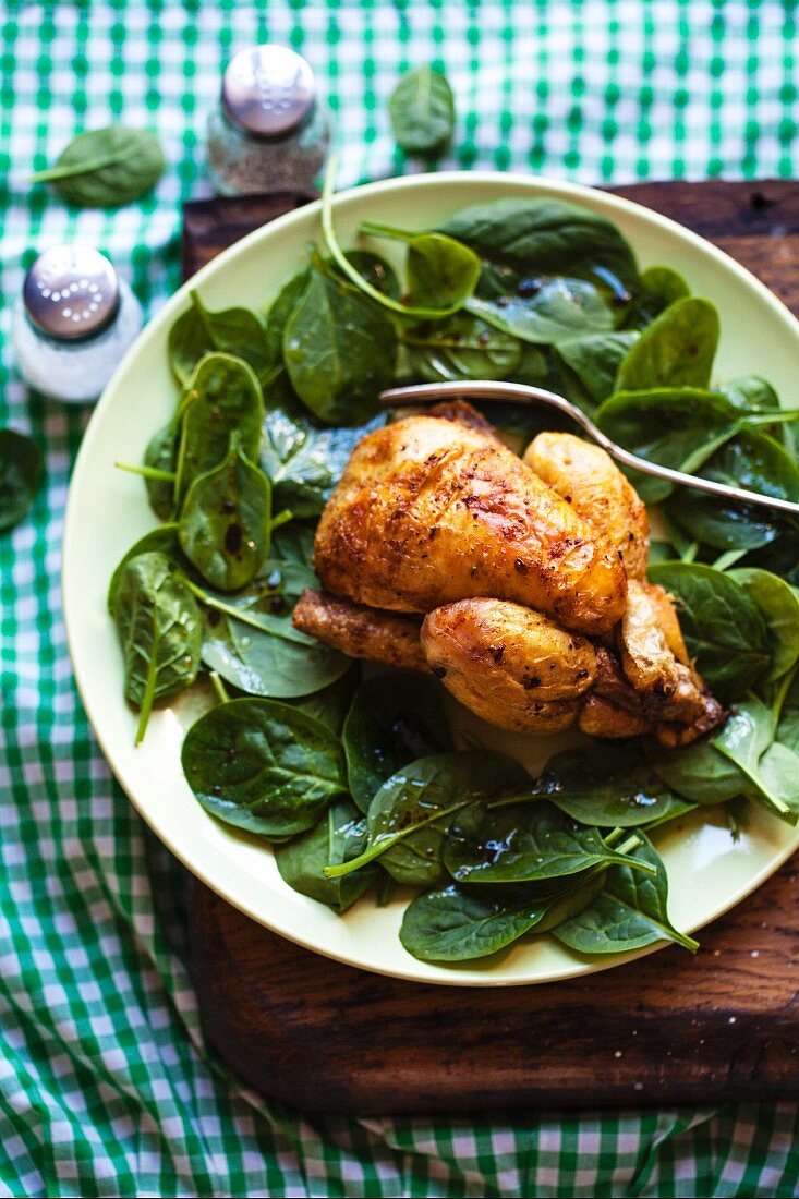 Roast chicken with a fork on fresh spinach