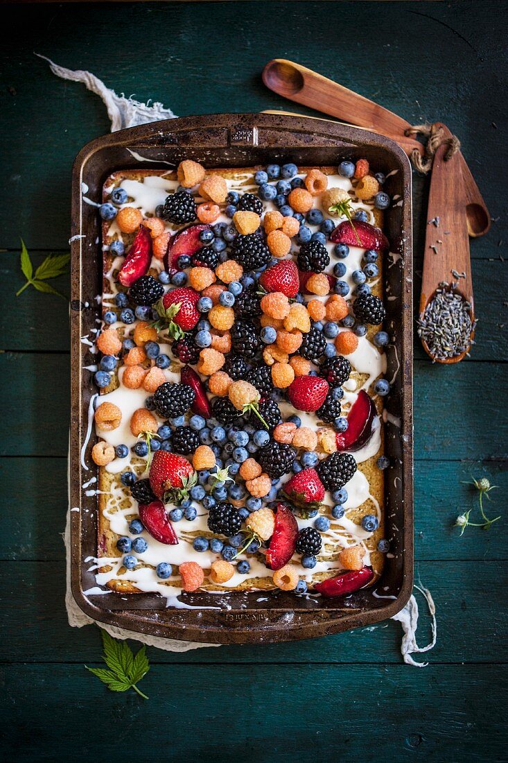 A Lavender Plum Berry Sheet Cake Topped with Mixed Berries and a Lemon Vanilla Glaze