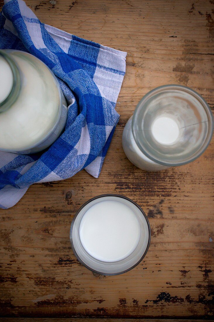 Stillleben mit Milch in Flasche, Karaffe & Glas (Aufsicht)