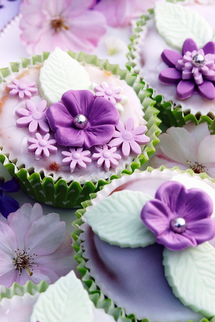 Muffins decorated with glacé icing and purple sugar flowers