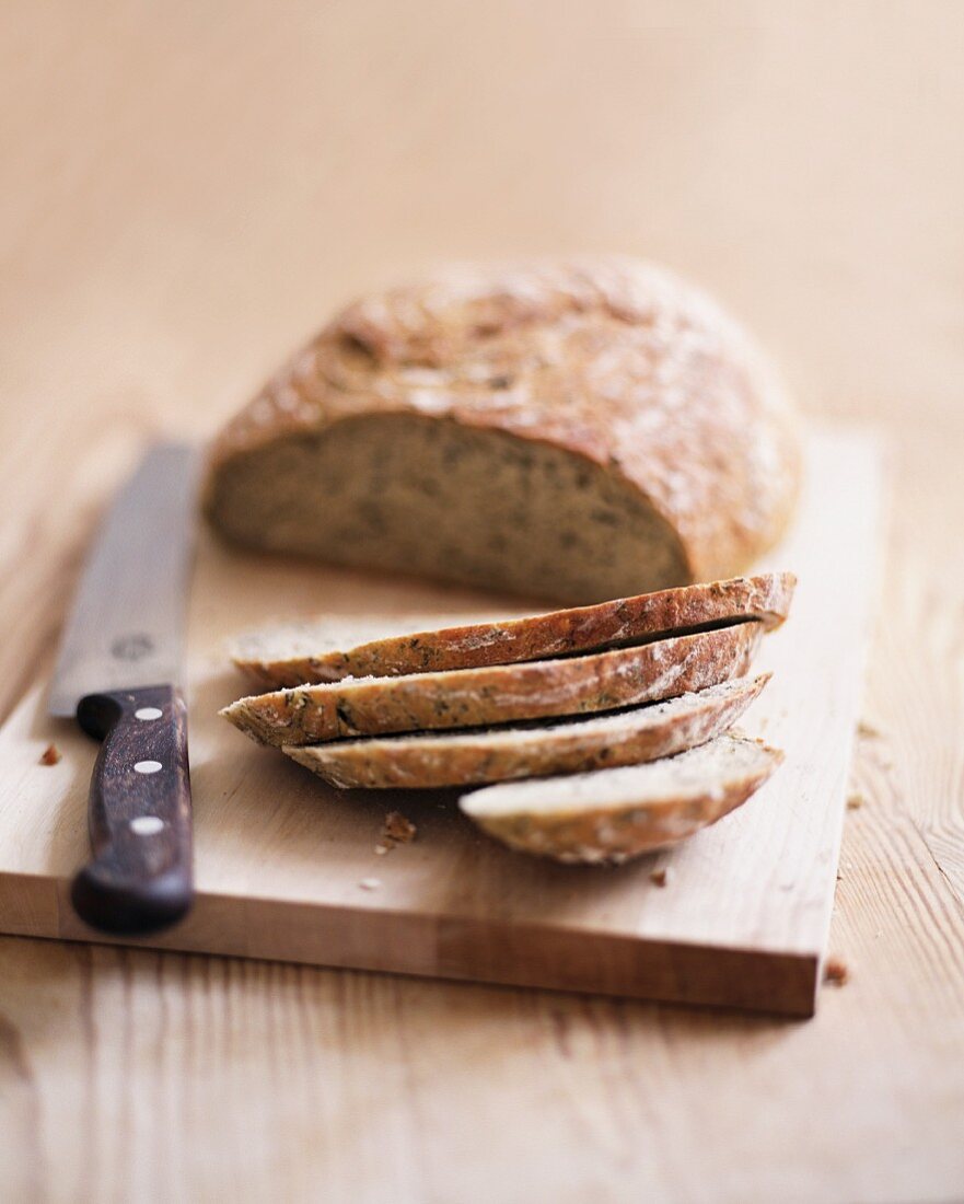 A partly sliced loaf of bread on a chopping board