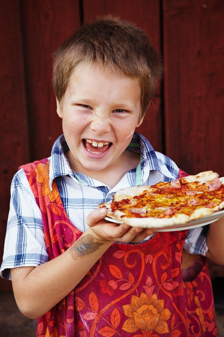 Boy holding pizza, laughing