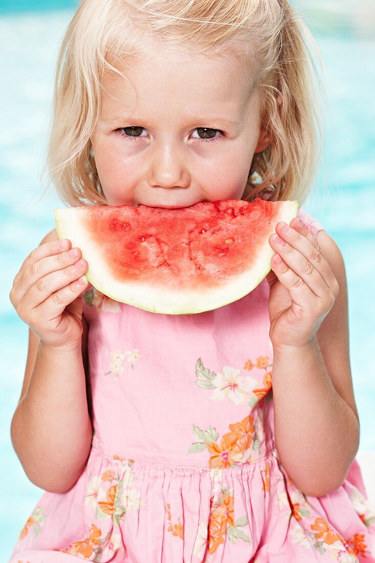 Blondes Mädchen beisst in eine Wassermelone