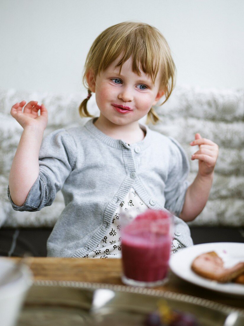 Kleines Mädchen mit Beerensmoothie