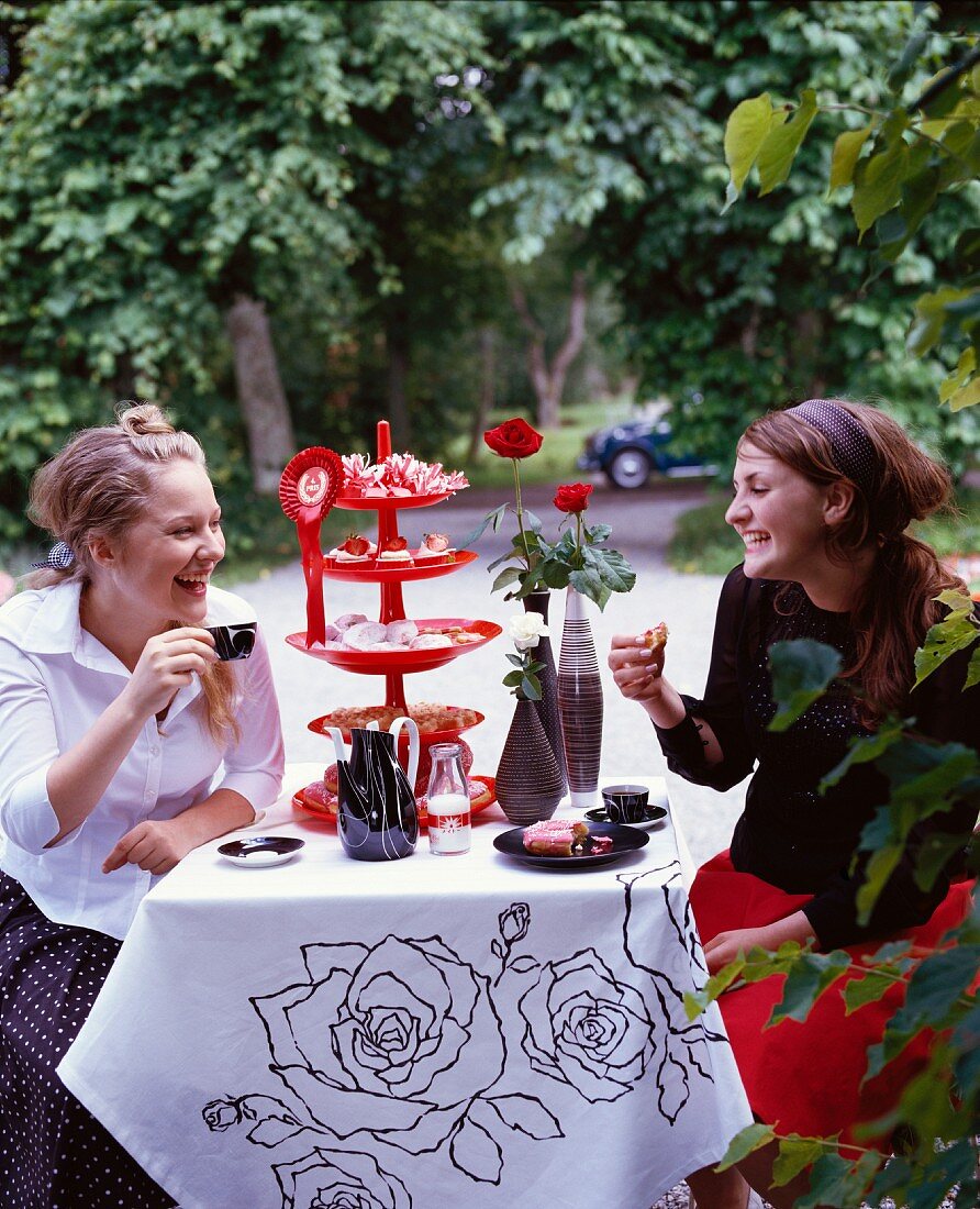 Two teenage girls sitting by a table in a park, Sweden.