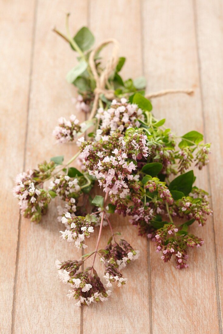 A bunch of flowering oregano on a wooden surface