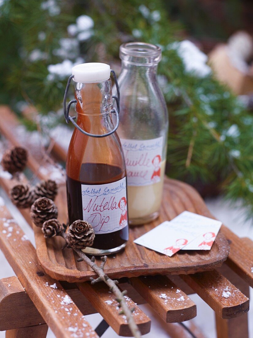 Two glass bottles of Nutella dip and vanilla sauce on a wooden board