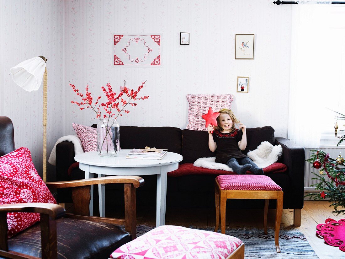 Girl sitting on sofa holding christmas decoration