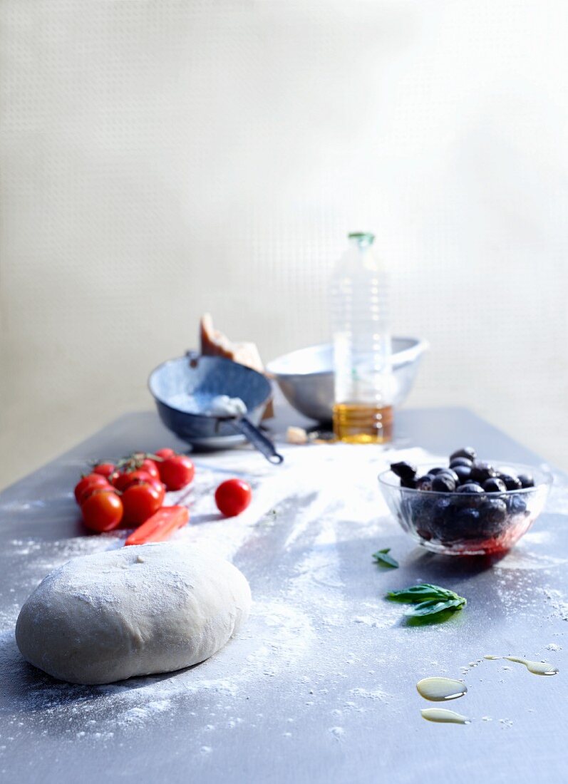 Dough and pizza ingredients on a kitchen worktop