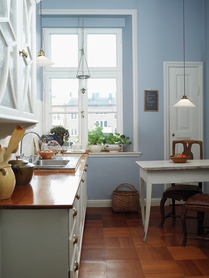 Traditional Scandinavian-style kitchen-dining room painted sky blue with old, glass pendant lamps