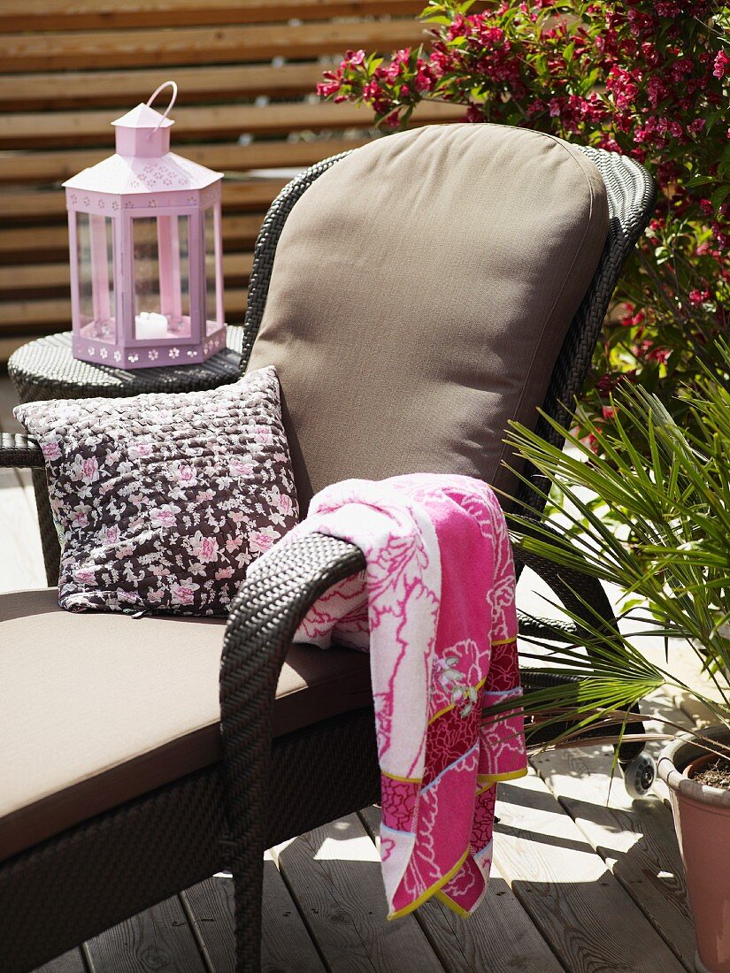 Lounger with cushion, towel and scatter cushion in front of lantern on side table