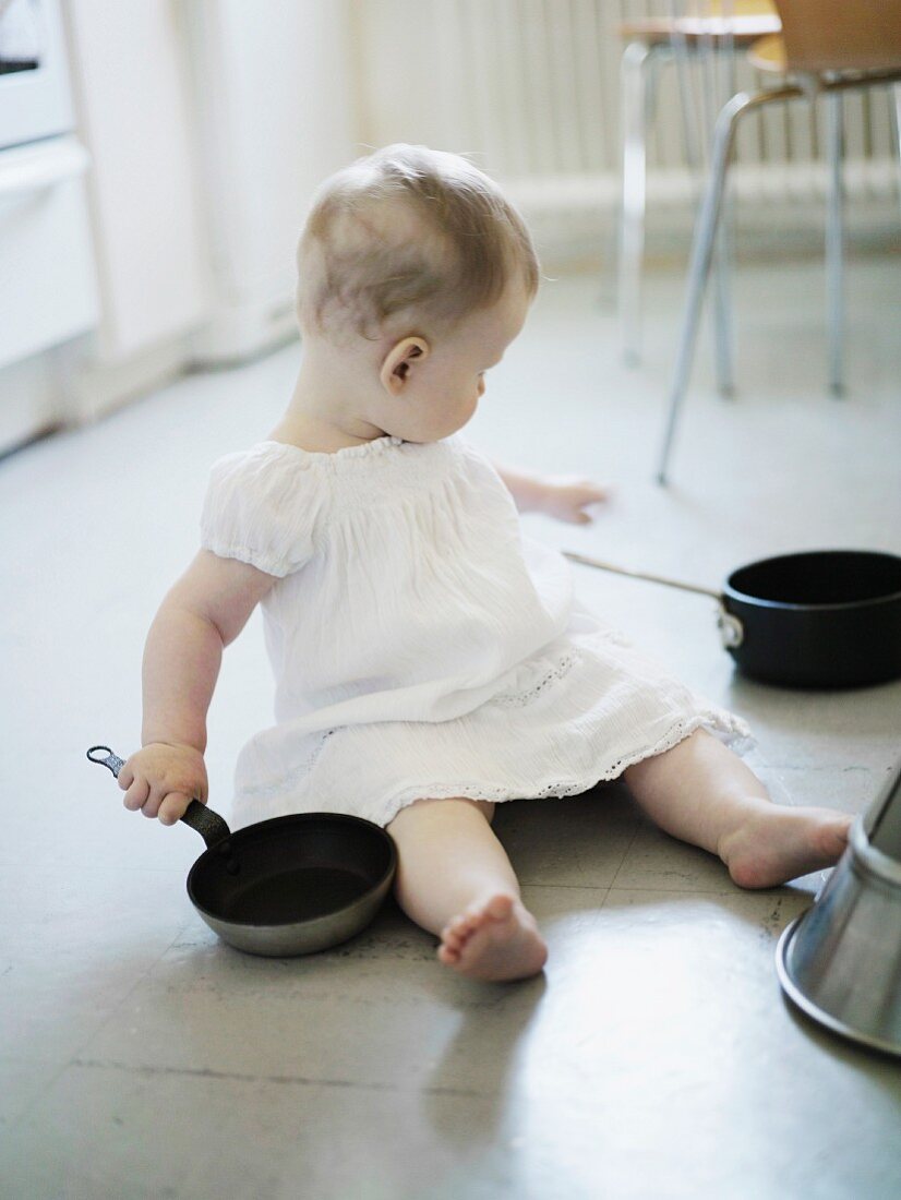 A little girl playing in a kitchen