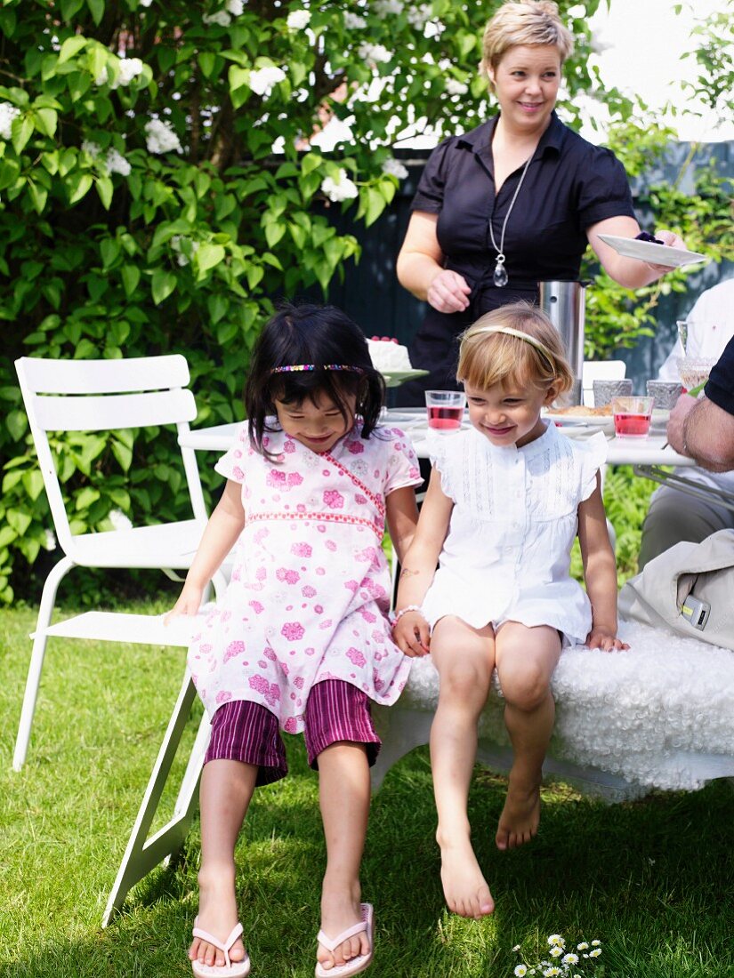 Girls and woman with refreshing drinks on garden table