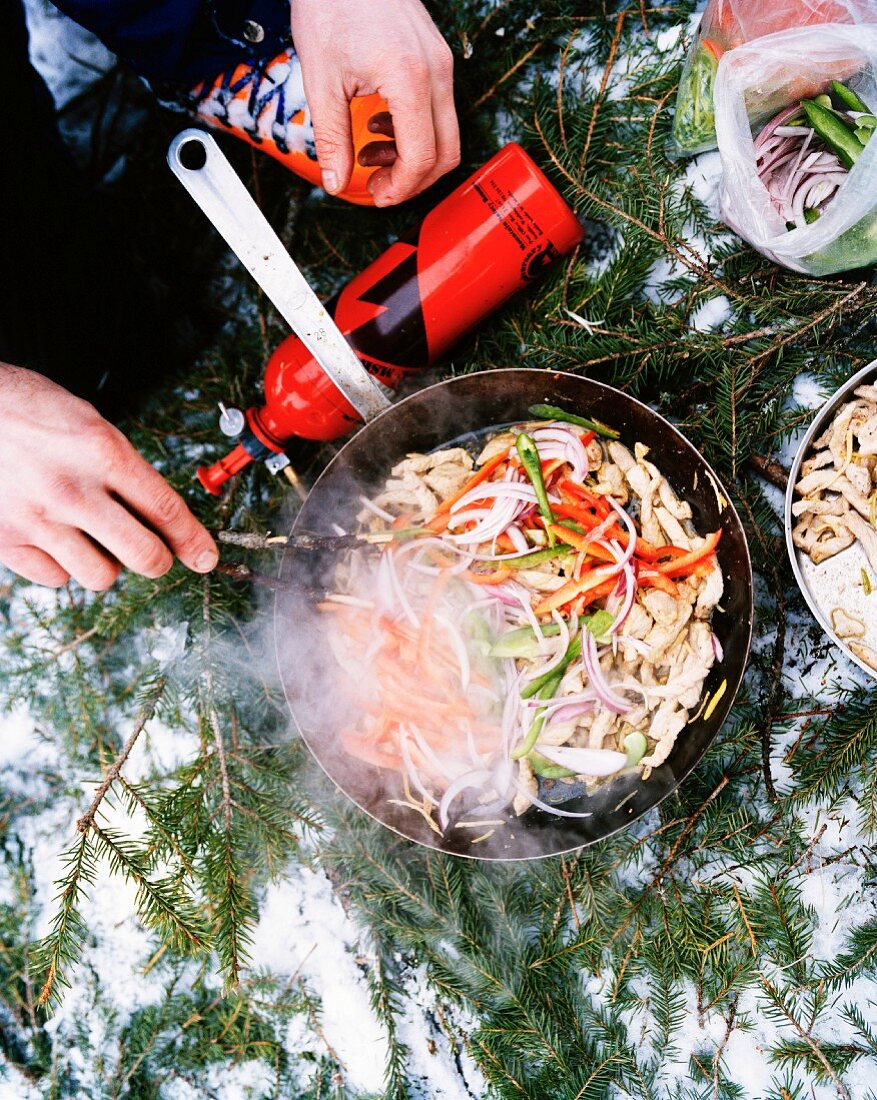 Campinggrill mit Wokpfanne auf schneebedecktem Waldboden