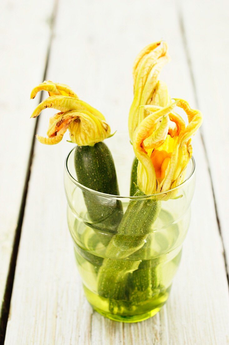 Small courgettes with courgette flowers in a glass of water