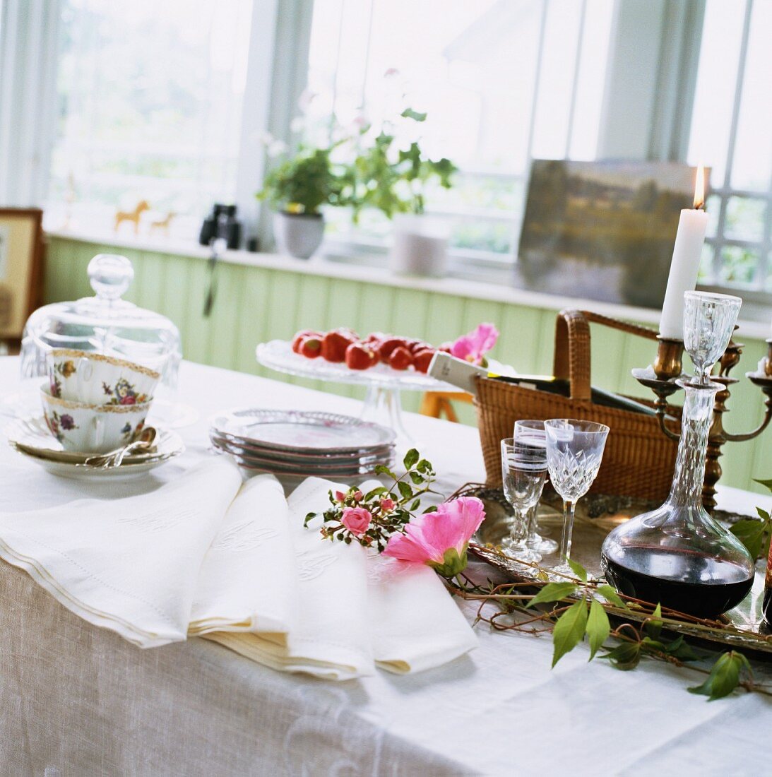 Coffee service and crystal carafe of liqueur on table with white tablecloth