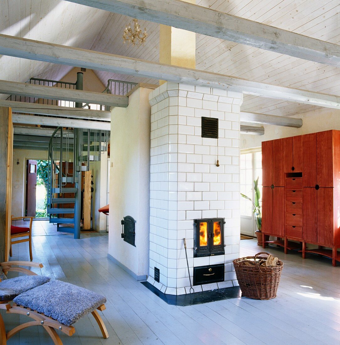 Tiled stove in open-plan interior with mezzanine in roof space