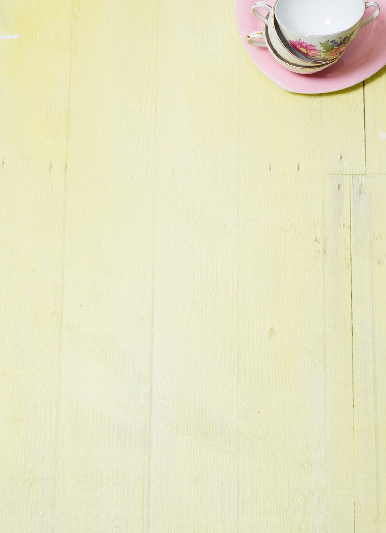 Stacked porcelain cups on a wooden surface painted a pale shade of green