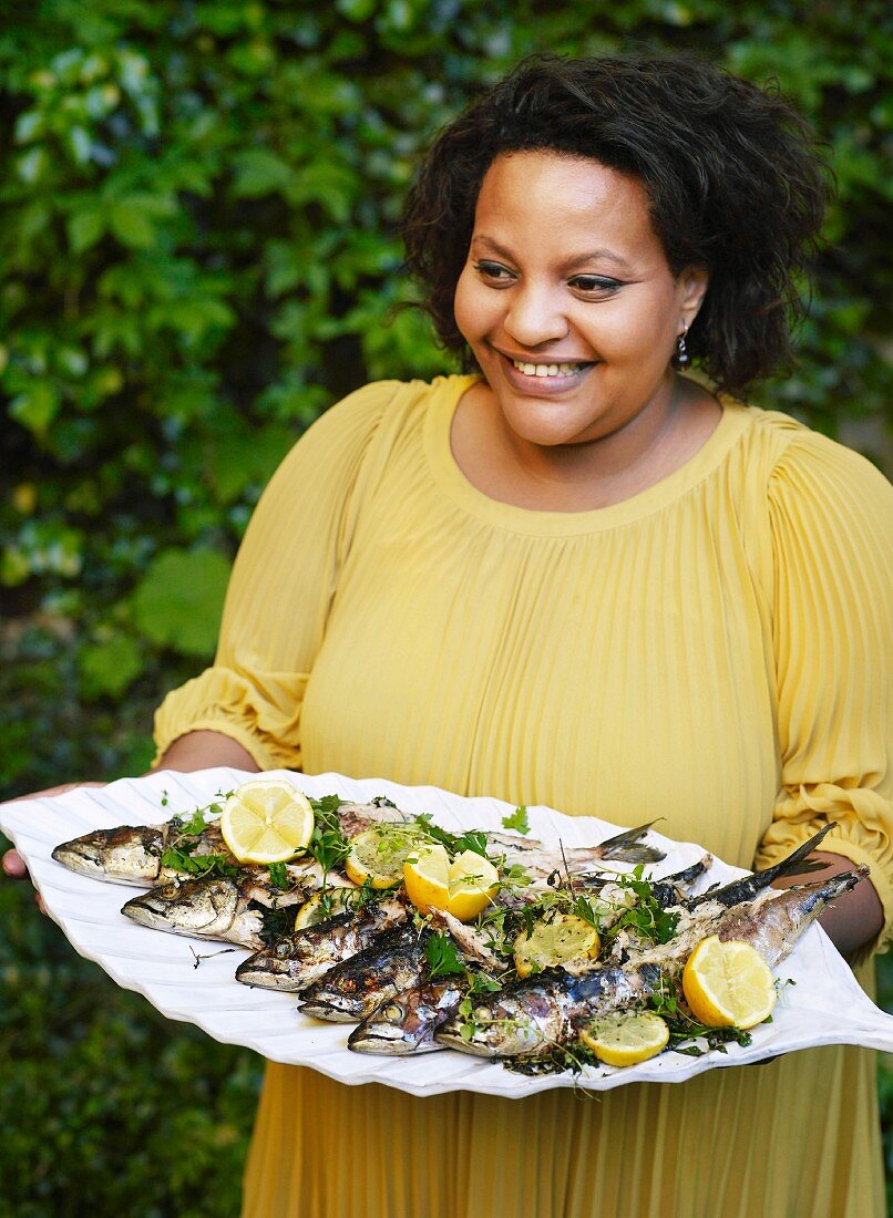 Woman carrying tray of grilled fish