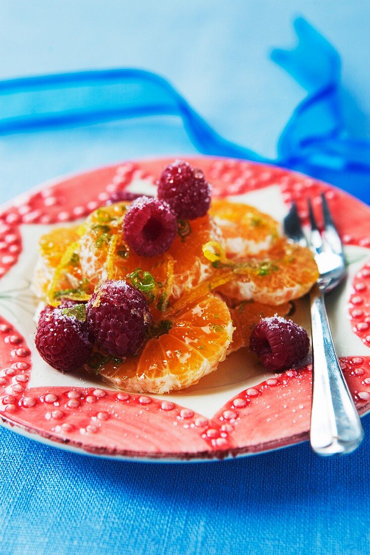 Raspberry and orange in plate, close-up