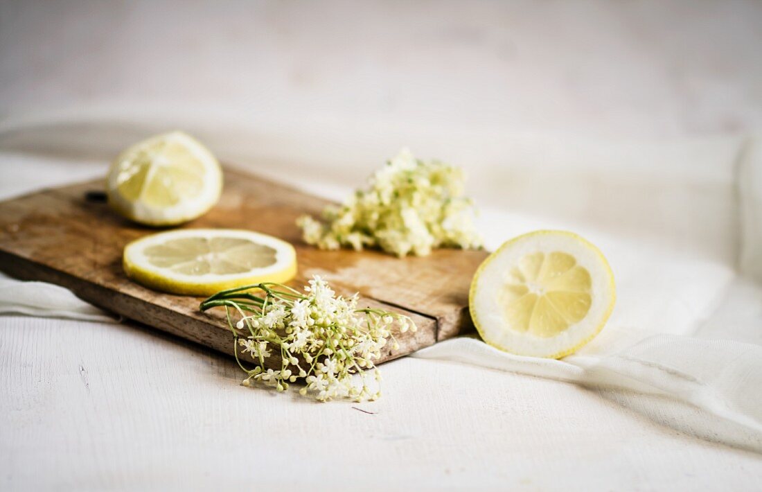 Elderflowers and lemon slices on a small wooden board