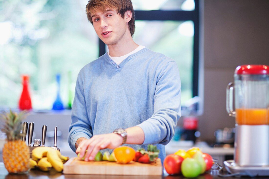 Young man in kitchen preparing fruit drink